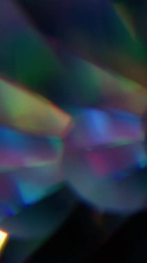 Dikey video. Parlak daireler. Bulanık yuvarlak işaret fişeği. Odaklanmamış floresan neon geometrik cam mercek dokusu soyut koyu siyah arkaplan üzerinde titreşiyor.