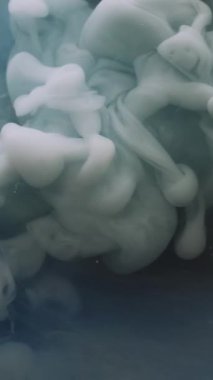 Dikey video. Duman arka planı. Sanat mürekkebi. Odaklanmamış mavi renk boya sıvı duman dokusu sıvı akışı sıçratır ruhani soyut koyu su üzerinde hareket eder.