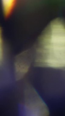 Dikey video. Optik doku. Bulanık ışık parlıyor. Odaklanmamış altın yeşili, pembe renkli mercek soyut sanat eserlerinde yanıp sönüyor..