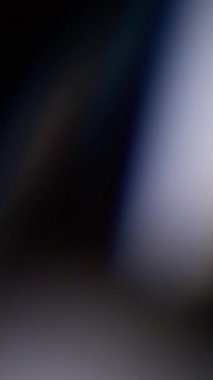 Dikey video. Işık sızıntısı. Bulanık yansıma. Odaklanmamış mavi renkli lens parıltısı soyut koyu siyah arkaplanda kıvılcım saçar..