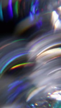 Dikey video. Işık daireleri. Bulanık gökkuşağı çizgileri. Odaklanamayan yeşil turuncu mercek soyut koyu siyah arkaplan üzerindeki kaleydoskop spektrumunu parlatmaktadır..