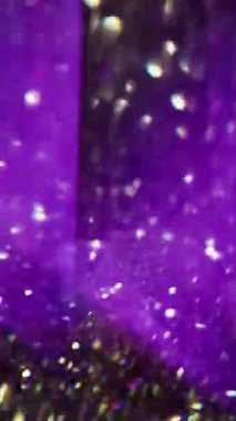 Dikey video. Parlak üçgenler. Odaklanamayan enerji geometrisi. Bulanık bokeh ışıklı arka planda hareket eden yeşil mavi mor çok renkli mercek..