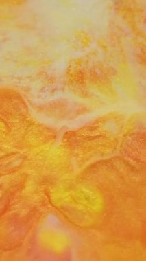 Dikey video. Metalik mürekkep. Parlak karışım. Renk sıvısı akışı parıldayan pigment sızıntısı. Işıl ışıl portakal suyu soyut arkaplanı bulanıklaştırır.