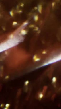 Dikey video. Üçgen sanatı. Odaklanmamış kıvılcımlar. Yeşil mavi, mor, çok renkli, pırıl pırıl bir lens. Bokeh efektli, soyut, bulanık bir arkaplanda parıldıyor..