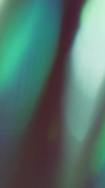 Dikey video. Gökkuşağı lazeri. Bulanık arkaplan. Odaklanmamış yeşil mor renkli lens soyut bokeh ışık sanatında parıltı deseni.