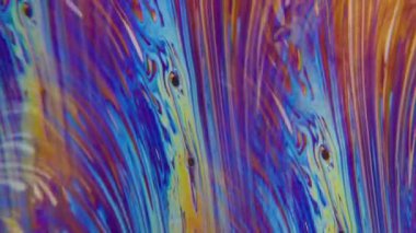 Dikey video. Yakıt dokusu. Hafif sıvı. Odaklanamayan sarı yeşil renkli girdaplı mor mürekkep damlacıkları soyut arkaplanda yüzüyor..