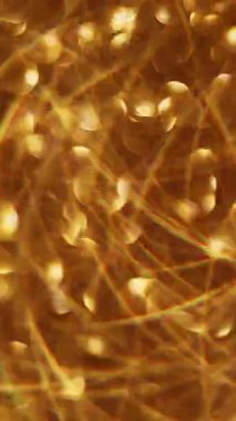 Dikey video. Hafif bir çelenk. Odaklanamayan altın parıltı. Işıl ışıl sarı, yanıp sönen daireler soyut Bokeh üzerinde hareket ederken modern arka plan bulanıklaştı..