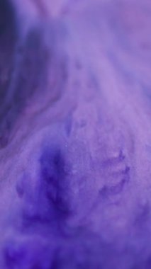 Dikey video. Mürekkep sanatı. Çözülmüş mermer boya. Mor yanıp sönen parlak dumanlı boya dokusu bulanık, aydınlık, modern arka planı açıyor..