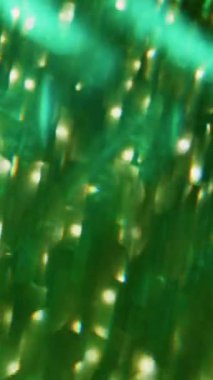 Dikey video. Parlak ışıklar. Odaklanamayan şenlik atmosferi. Bulanık soyut modern arkaplanda Bokeh efektli yeşil mavi geometrik uçan.