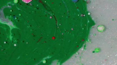 Parlak boya. Mürekkep döküldü. Soyut yaratıcı sanat arka planında beyaz suyun üzerinde yüzen, pembemsi yeşil, beyaz, parlak yağ rengi..