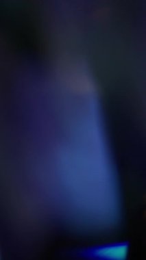 Dikey video. Parlak ışık. Bulanık işaret fişeği. Odaklanmamış sarı mavi renk titreşimli desen spektrum gökkuşağı soyut koyu siyah arkaplan.
