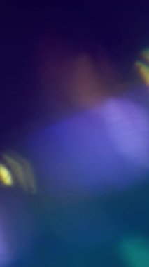Dikey video. Optik ışıltı. Bulanık spektrumlu işaret fişeği. Odaksız mor yeşil renkli lens soyut koyu siyah arkaplan üzerinde ışık deseni kıvılcımları saçar.