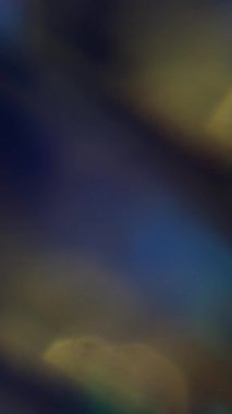 Dikey video. Parlak lens. Bulanık kıvılcım dokusu. Odaklanamayan sarı mor çok renkli al ışık soyut sanat koyu siyah arkaplanda titreşiyor.