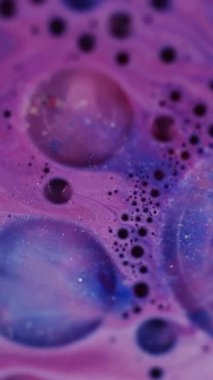 Dikey video. Işıl ışıl akıyor. Odaklanmamış köpük dokusu. Mavi pembe su renkli kabarcıklar sıvı bulanık bokeh hafif modern sanat arka planını açıyor.