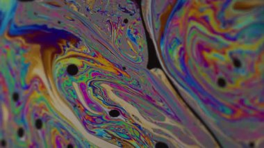 Dikey video. Yağ damlası. Mürekkep karışımı. Odaklanmamış yeşil mavi renk pembe mor yuvarlak doku soyut koyu siyah arkaplan üzerinde yüzüyor.