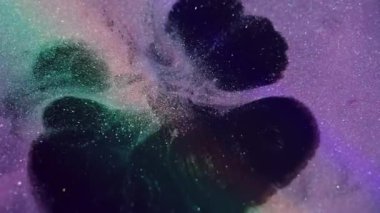 Boya serpintisi. Mürekkep sıçraması. Odaklanamayan mor yeşil renkli parlak sıvı soyut koyu siyah arka planda yayılıyor..