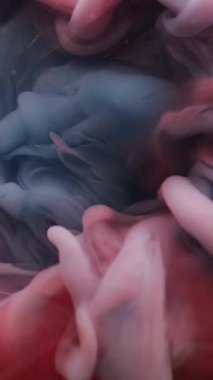 Dikey video. Duman girdabı. Boya suyu karışımı. Soyut sanat akrilik arka planda odaksız kırmızı boya sıvı duman bulutu sıvısı.