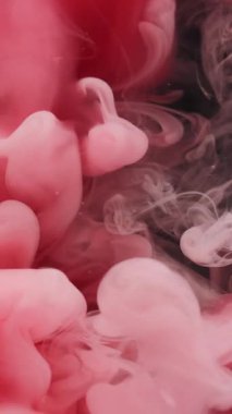 Dikey video. Duman sıçrıyor. Boya buharı. Soyut karanlık sanat arka planında çözünmüş pembe renk sisi sıvı ruhani sis suyu buharı.
