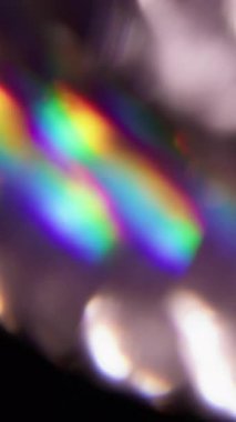 Dikey video. Parlak doku. Bulanık gökkuşağı. Odaklanmamış mavi yeşil renkli parıltı soyut koyu siyah sanat arka planında göz kamaştırıcı parıltı.