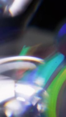 Dikey video. Retro optik. Bulanık flaş spektrumu. Odaklanmamış yeşil turuncu mercek soyut koyu siyah arkaplanda yanıp sönen ışık yansıması.