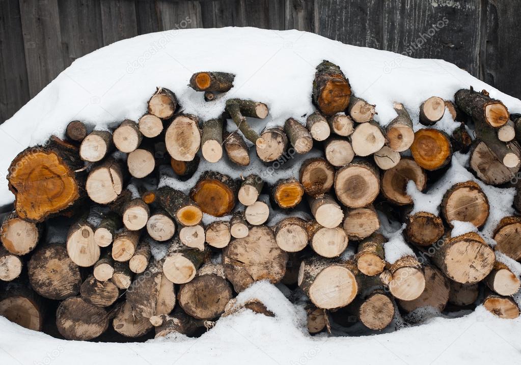 stack of  snowy firewood on  wooden background