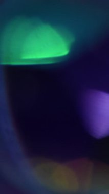 Dikey video. İşaret fişeği arka planı. Bulanık parlak yuvarlak. Odaklanmamış mor yeşil kıvılcım kıvılcımlı çerçeve ışığı soyut bokeh koyu siyah sanat üzerinde yüzüyor.