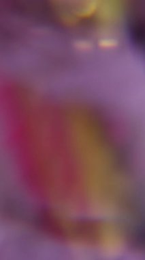 Dikey video. Işık efekti. Görüntü pırıltısı. Odaklanmamış mor sarı çok renkli lens soyut sanat ışığı arka planında gökkuşağı alevi yanıp sönüyor.