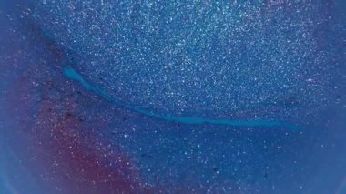 Canlı boya sıvısı. Mavi akış. Soyut yaratıcı akrilik sanat arka planında sönük mor renkli sim damlası yüzüyor.