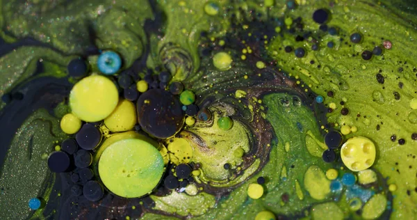 Renkli boya. Köpük jeli. Soyut akrilik sanat arka planında yüzen sıvı sıvı yağ damlacığının etrafında çözünmüş sarı mavi parıltı.