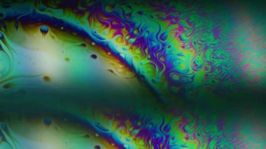 Gökkuşağı emülsiyonu çözüldü. Yüzen mürekkep. Siyah arka planda çift renkli sıvı çizgili yağ girdabı. Mercek prizması soyut mor yeşil gradyan parıltısı.