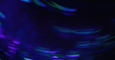 Odaklanamayan kıvılcım. Parıldayan bir işaret fişeği. Renkli neon ışınları siyah arkaplanda akar. Soyut floresan mavi yeşil yansıma.