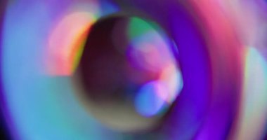Yuvarlak bokeh prizması. Kaçak aydınlatma. Neon renkli küre siyaha yansıyan kaleydoskop dönüşü. Mor kırmızı yeşil soyut bulanık arkaplan.