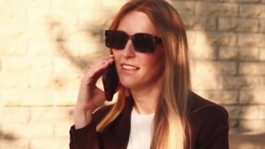 Akıllıca bir telefon görüşmesi. İş molası. Güneş gözlüklü, kendinden emin bir kadın dışarıda dostça bir telefon görüşmesi yapıyor..