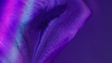 Mürekkep küpü. Akan neon çizgiler. Soyut arkaplandaki su damlacıklarında çözünmüş pembe renkli gökkuşağı boyası.