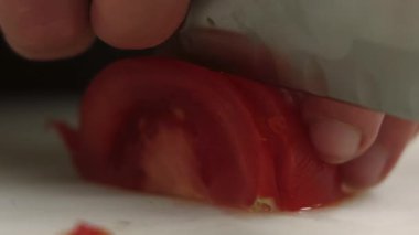 Yemek pişirme tekniği. Domates doğrama. Şefin elleri keskin bıçakla hazırlanıyor. Mutfak tahtasındaki vejetaryen yemeği için taze taze kırmızı malzemeler..