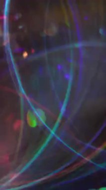 Dikey video. Renkli disko parıltısı. Bulanık, neşeli bir ışık. Soyut, parlak, koyu arkaplanda sarı, turuncu, mor daireler..