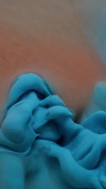 Dikey video. Mürekkep damlası patlaması. Suyu boya. Odaklanmamış mavi turuncu renkli ruhani sıçrama sıvısı soyut sanat arka planında yüzüyor..