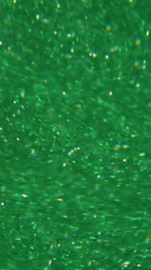 Dikey video. Görüntü kıvılcımı. Parlak ışık. Soyut koyu siyah arkaplanda yeşil mavi kırmızı çok renkli mercek yanıp sönüyor.