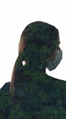 Dikey video. Hava kirliliği. Doğa koruma. Sis tozlu orman ağaçlarının hava manzarası. Yüzünde maske olan kadın silueti beyaza izole edilmiş..