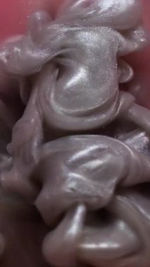 Dikey video. Dalga dokusu. Boya karışımı. Odaklanmamış mor turuncu dumanlı kimyasallar soyut sanat arka planında parıldıyor..