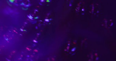 Parıltı söndü. Kristal titreşimli. Mor kırmızı, pürüzlü, parlak dokular, dönen akış. Siyah arkaplanda soyut ışıltı.