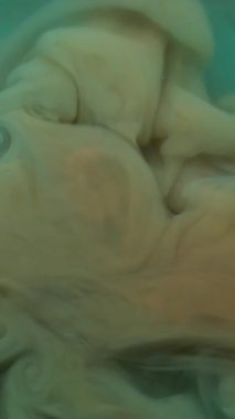 Dikey video. Dalga mürekkebi. Sıçrama sanatı. Soyut arkaplanda büyüyen akrilik sıvı pigmenti çözünmüş mavi renkli su kimyasal akışı.