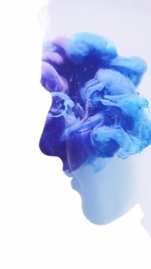 Dikey video. İyileştirici enerji. Zihin eğlencesi. Mavi mürekkep dumanı bulutu, çift pozlama profili, beyaz üzerine izole edilmiş barışçıl bir kadının silüeti..