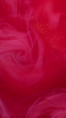 Dikey video. Duman sıçrıyor. Boya buharı. Odaklanmamış kırmızı pembe renk parçacıkları soyut arkaplanda yüzen sis suyu akrilik akış dumanı.