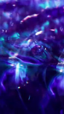 Dikey video. Parlak sıvı. Odaklanamayan kabarcık parıltısı. Bulanık mavi mor renk bokeh açık arkaplanda parlak parçacıklar parlıyor.