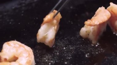 Kızarmış karides. Mutfağa koşun. Aperatif protein bileşenini siyah tavaya cımbızla atmak. Lezzetli kıtır kıtır deniz ürünleri..
