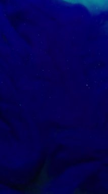 Dikey video. Duman boyası. Akrilik pigment. Odaklanamayan mavi renk sıvı kimyasal sim soyut sanat arka planına yayılan parlak sis..