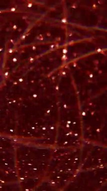 Dikey video. Bulanık renk parlıyor. Parıltı. Şeffaf dokuya odaklanmış parlak çelenk. Kırmızı ışık soyut sanat arka planı..