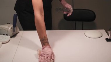 Güzellik salonu. Dezenfekte çalışmaları yüzeye çıkıyor. Kadın manikürcü, iş yerini dikkatlice temizlerken antiseptik dezenfektan kullanıyor..