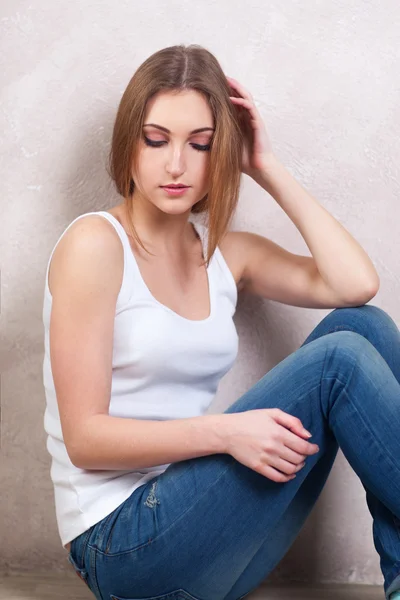 La donna premurosa si siede su un piano vicino a una parete bianca — Foto Stock